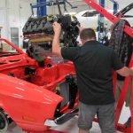 A man working on an old red car