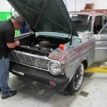 A man working on an old car in a garage.