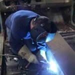 A man welding in an industrial setting.