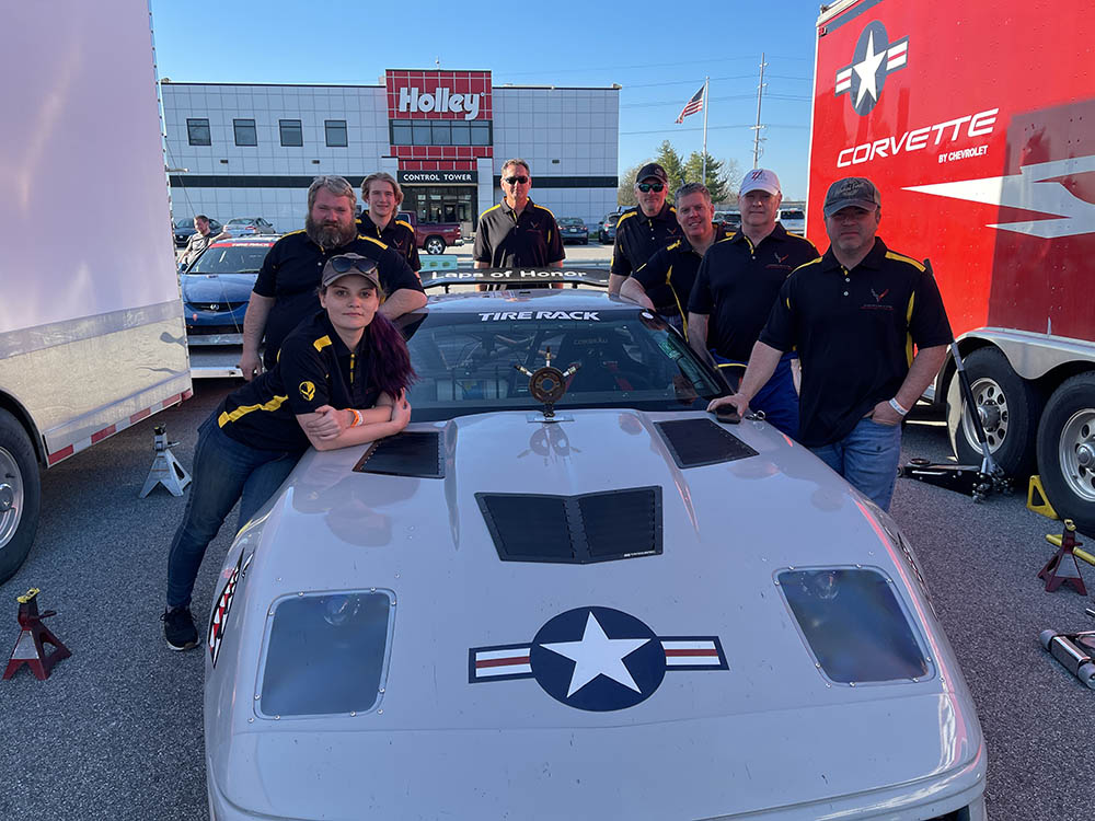 A group of men standing around a white car.