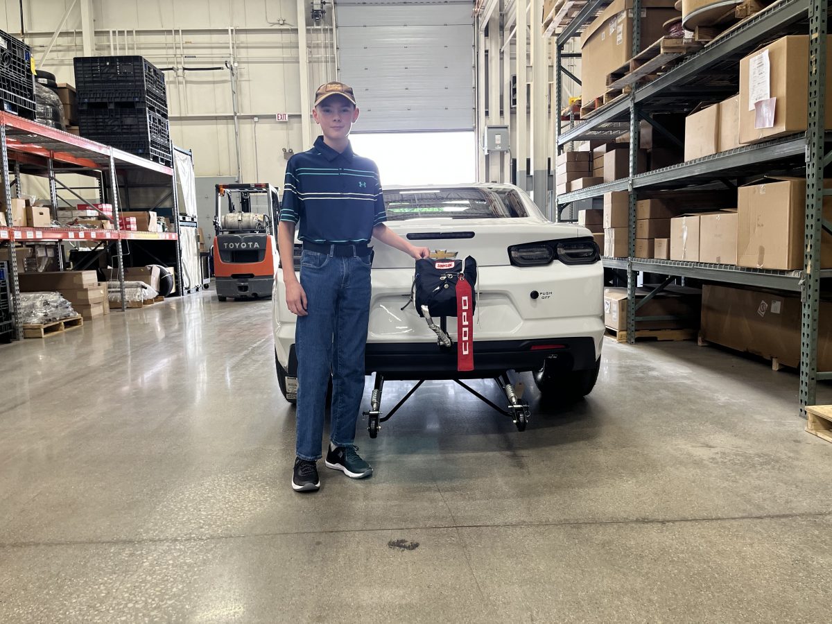 A man standing next to a white car in a warehouse.